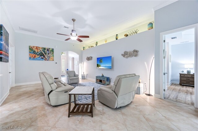 living room with baseboards, visible vents, arched walkways, a ceiling fan, and ornamental molding