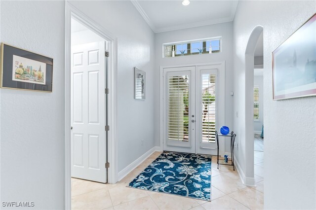 entrance foyer with baseboards, arched walkways, ornamental molding, tile patterned floors, and french doors