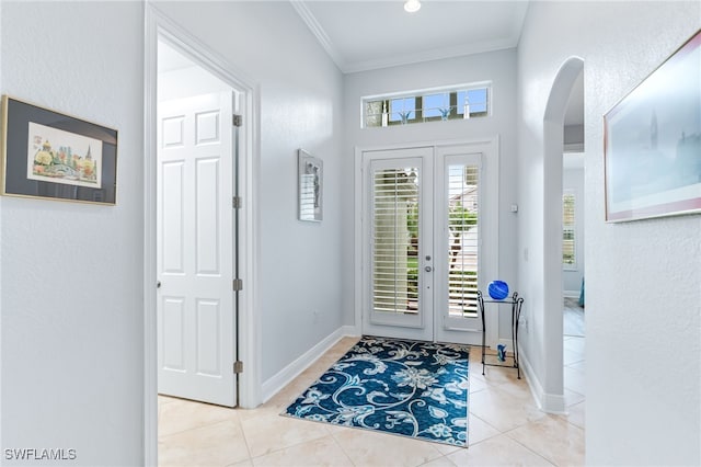 tiled foyer entrance with arched walkways, french doors, crown molding, and baseboards