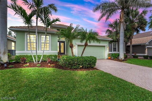 view of front facade with an attached garage, stucco siding, decorative driveway, and a front yard