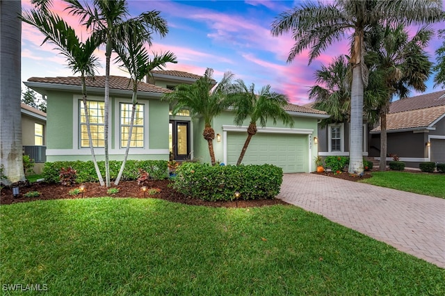 8732 Banyan Bay Blvd, Fort Myers, FL 33908 - view of front of home with stucco siding, driveway, a tile roof, an attached garage, and a yard