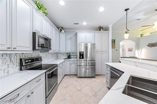 8732 Banyan Bay Blvd, Fort Myers, FL 33908 - kitchen with stainless steel appliances, arched walkways, ornamental molding, tasteful backsplash, and white cabinetry