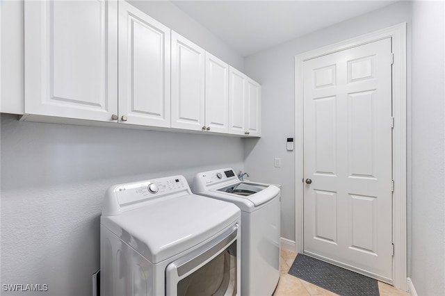 washroom featuring cabinet space, independent washer and dryer, baseboards, and light tile patterned floors