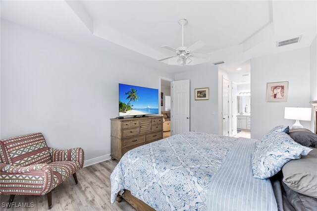 bedroom featuring visible vents, ensuite bath, baseboards, and wood finished floors