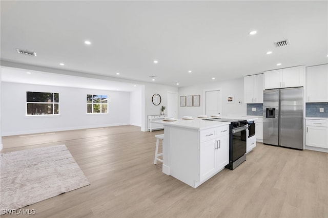 kitchen featuring black range with electric cooktop, light wood finished floors, stainless steel fridge, and visible vents