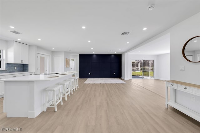 kitchen with tasteful backsplash, visible vents, light wood finished floors, and white cabinetry