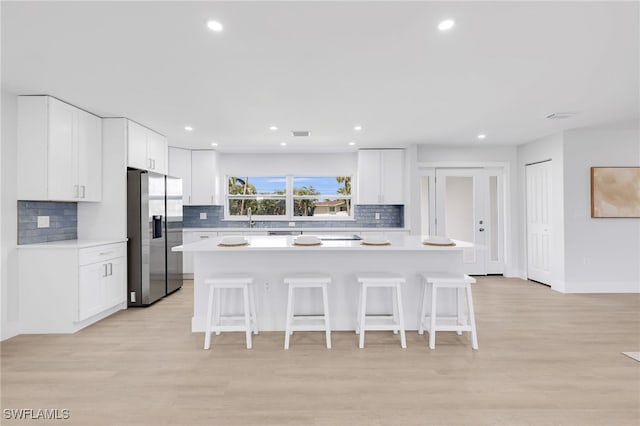 kitchen featuring white cabinets, a breakfast bar area, light countertops, and stainless steel fridge with ice dispenser