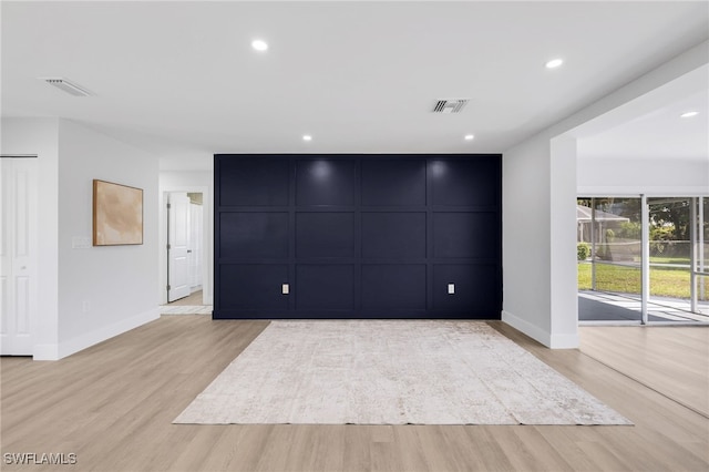 interior space with a decorative wall, recessed lighting, visible vents, and light wood-style floors