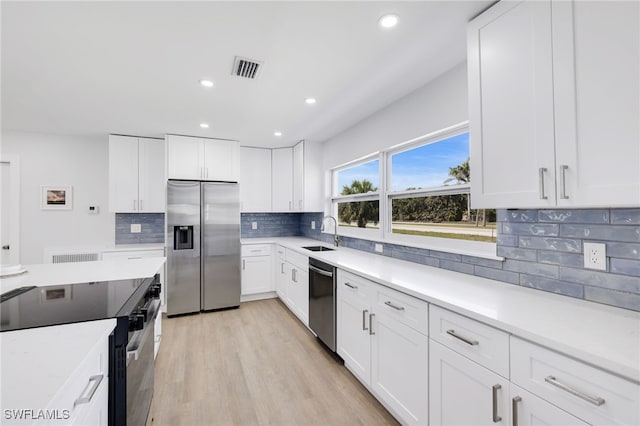 kitchen with stainless steel appliances, a sink, visible vents, light countertops, and light wood finished floors