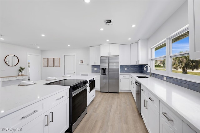 kitchen with stainless steel appliances, light countertops, visible vents, decorative backsplash, and a sink