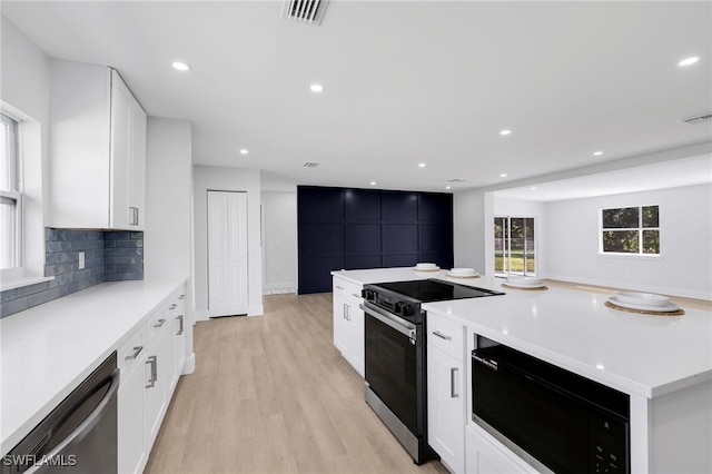 kitchen featuring visible vents, decorative backsplash, dishwasher, black microwave, and range with electric stovetop