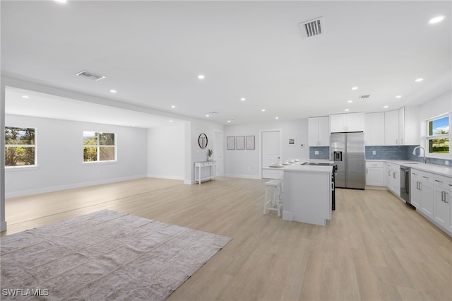 kitchen featuring stainless steel appliances, open floor plan, visible vents, and a kitchen island