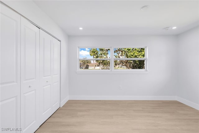 unfurnished bedroom featuring light wood-style flooring, baseboards, a closet, and recessed lighting