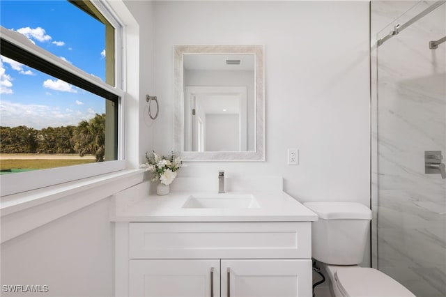 bathroom featuring visible vents, vanity, toilet, and walk in shower