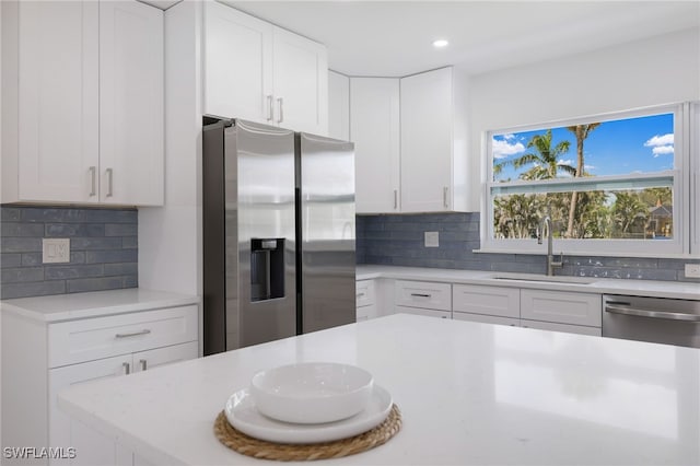 kitchen with white cabinets, a sink, stainless steel appliances, backsplash, and recessed lighting