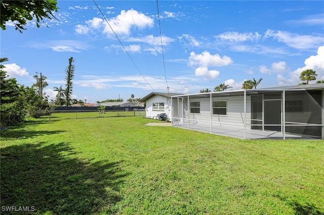 rear view of property featuring a yard, a patio area, fence, and a sunroom