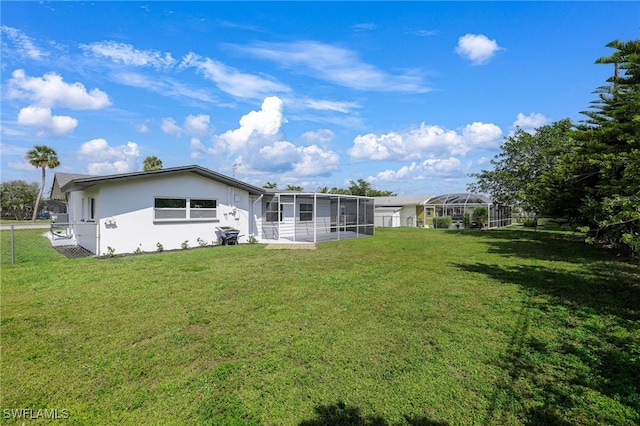 rear view of property with a sunroom, fence, a lawn, and stucco siding