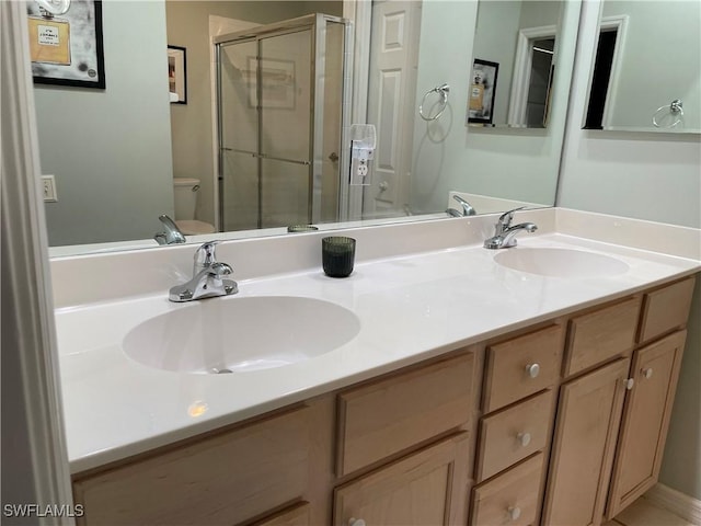 full bathroom with double vanity, a sink, toilet, and a shower stall