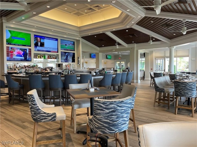 dining space featuring a dry bar, decorative columns, ceiling fan, light wood-style flooring, and ornamental molding