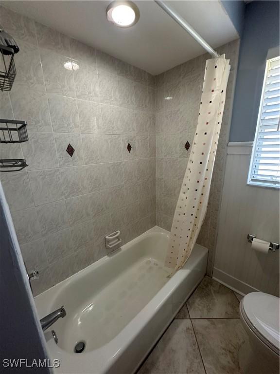 full bath featuring a wainscoted wall, toilet, and shower / tub combo with curtain