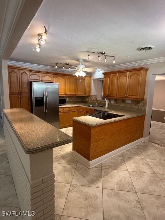 kitchen featuring stainless steel appliances, a sink, visible vents, brown cabinetry, and crown molding