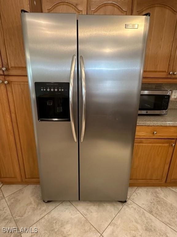 kitchen featuring light tile patterned floors, stainless steel appliances, and brown cabinetry