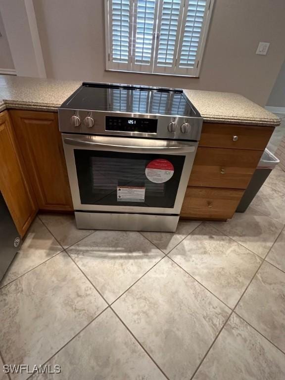 kitchen with stainless steel range with electric stovetop, light countertops, and brown cabinetry