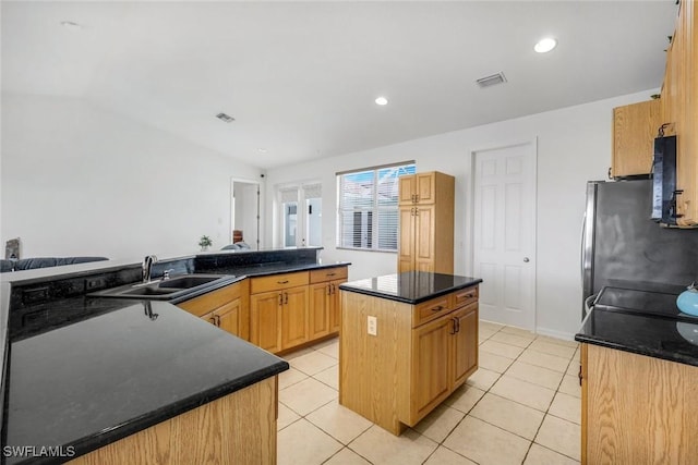 kitchen featuring visible vents, a sink, a center island, freestanding refrigerator, and light tile patterned floors