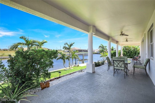 view of patio with outdoor dining area, a water view, and a ceiling fan