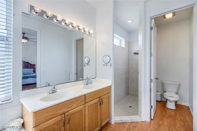 bathroom with a sink, a tile shower, double vanity, and tile patterned flooring