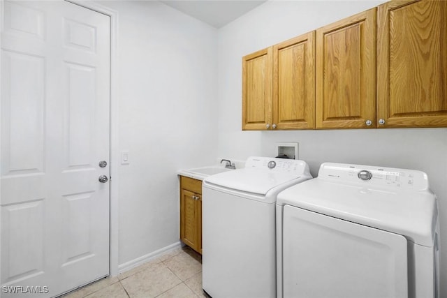 washroom featuring light tile patterned floors, baseboards, cabinet space, a sink, and washer and clothes dryer