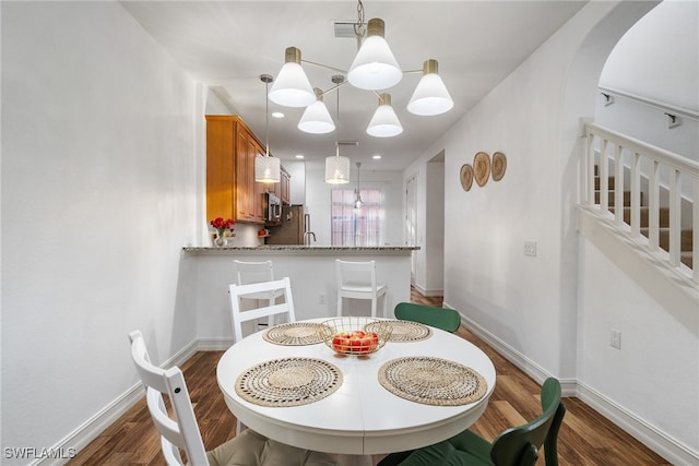 dining room with stairway, wood finished floors, visible vents, and baseboards