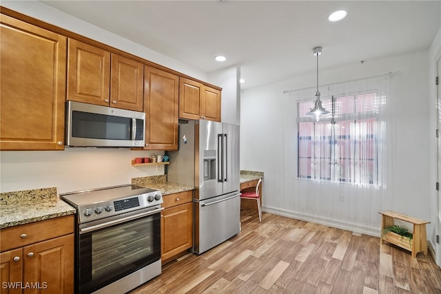 kitchen with light wood-type flooring, light stone countertops, appliances with stainless steel finishes, and brown cabinetry