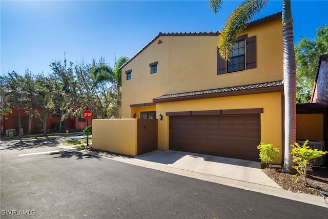 mediterranean / spanish-style home with concrete driveway, a tile roof, an attached garage, and stucco siding