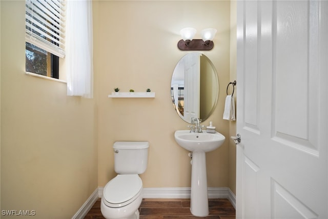 bathroom featuring a sink, wood finished floors, toilet, and baseboards