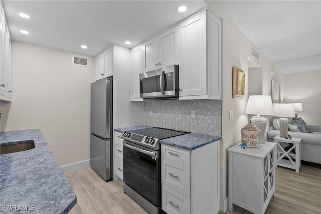 kitchen with visible vents, appliances with stainless steel finishes, light wood-style flooring, and decorative backsplash