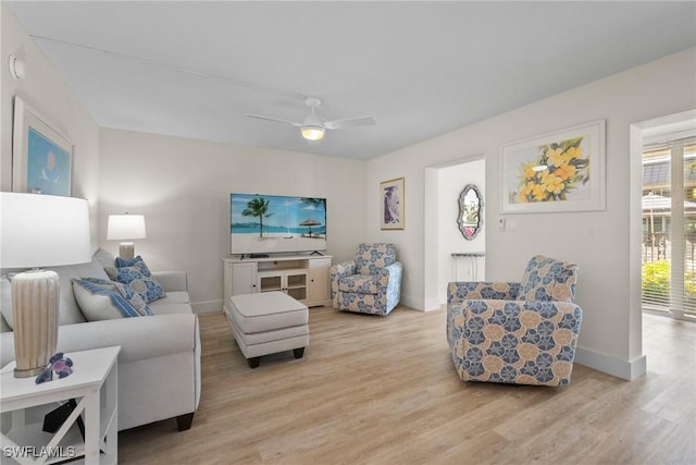 living area with ceiling fan, light wood-style flooring, and baseboards