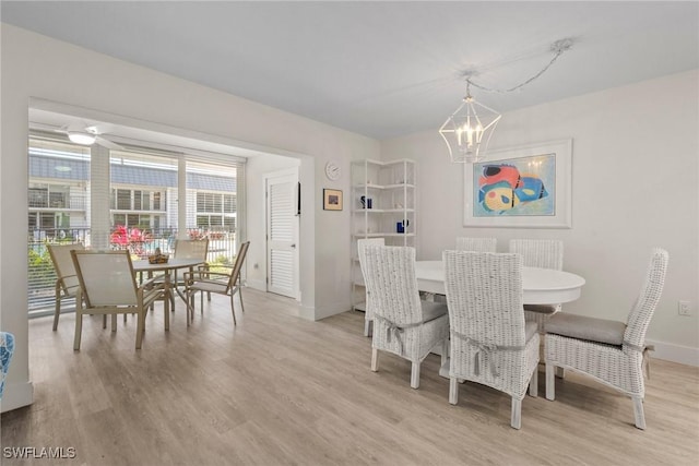 dining space featuring light wood finished floors, baseboards, and an inviting chandelier