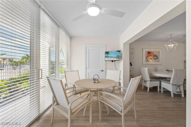 dining space featuring ceiling fan with notable chandelier and wood finished floors