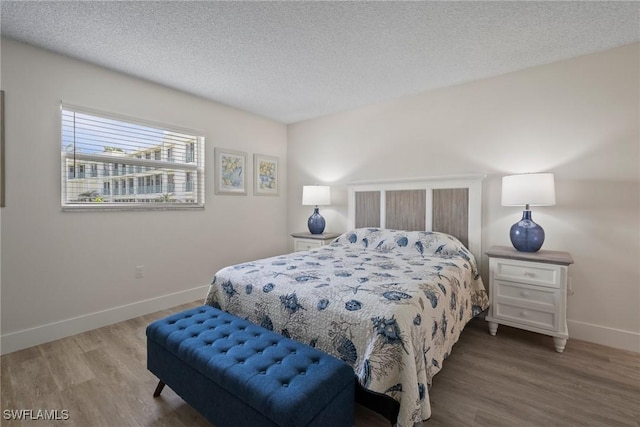 bedroom with a textured ceiling, wood finished floors, and baseboards