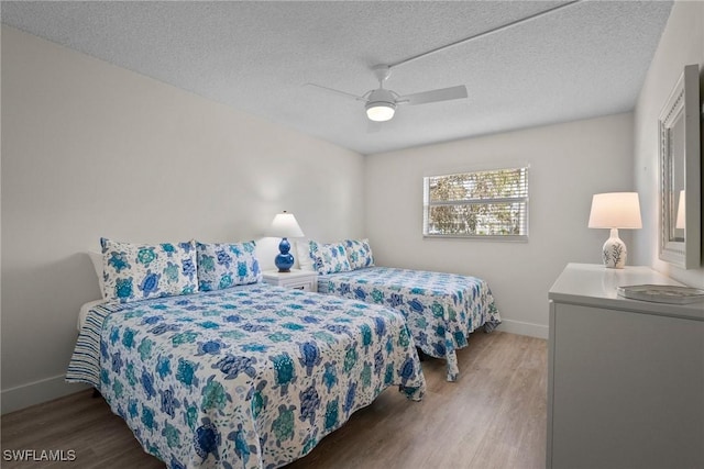 bedroom featuring a textured ceiling, wood finished floors, and baseboards