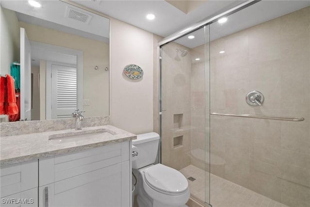 bathroom featuring visible vents, a shower stall, toilet, and vanity