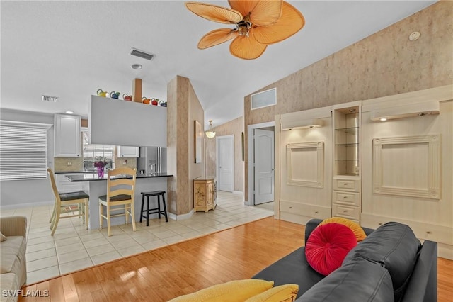 living room with light wood-style floors, visible vents, and a ceiling fan