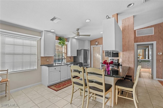 kitchen featuring visible vents, white cabinets, dark countertops, stainless steel appliances, and a sink