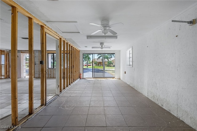 interior space with ceiling fan, a textured wall, and tile patterned floors