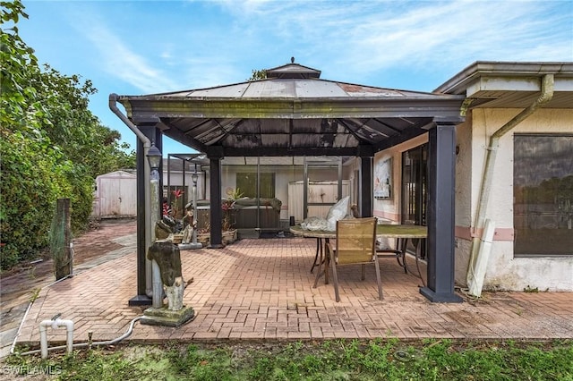 view of patio / terrace featuring an outbuilding, a gazebo, a shed, and a hot tub