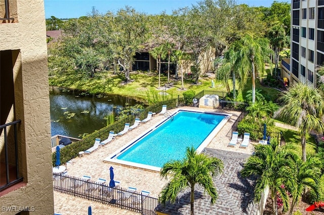 community pool featuring a patio, a water view, and fence