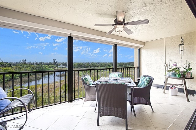 sunroom / solarium with ceiling fan and a water view