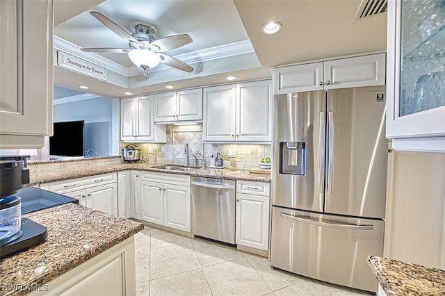 kitchen featuring appliances with stainless steel finishes, a raised ceiling, a sink, and ornamental molding