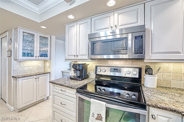 kitchen with stainless steel appliances, white cabinetry, crown molding, and light stone countertops